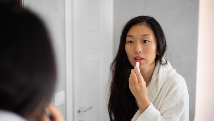 Ilustrasi lip care atau lipstik Asian Lady in bathroom mirror after shower, Applying lipstick