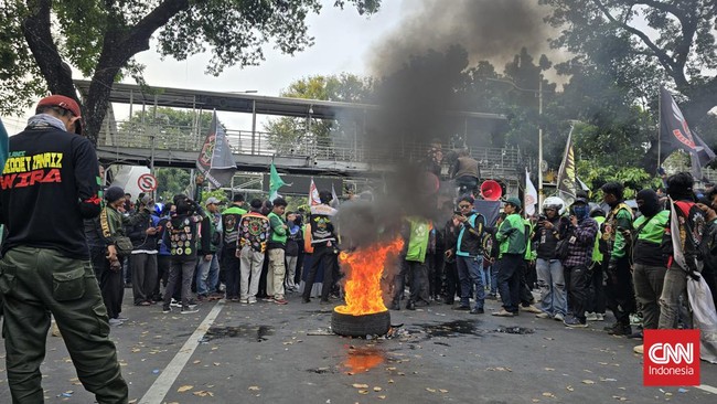 Massa tindakan pengemudi ojol membakar ban hingga melemparkan petasan ke arah abdi negara di Patung Kuda, Jakarta Pusat, Kamis (29/8).