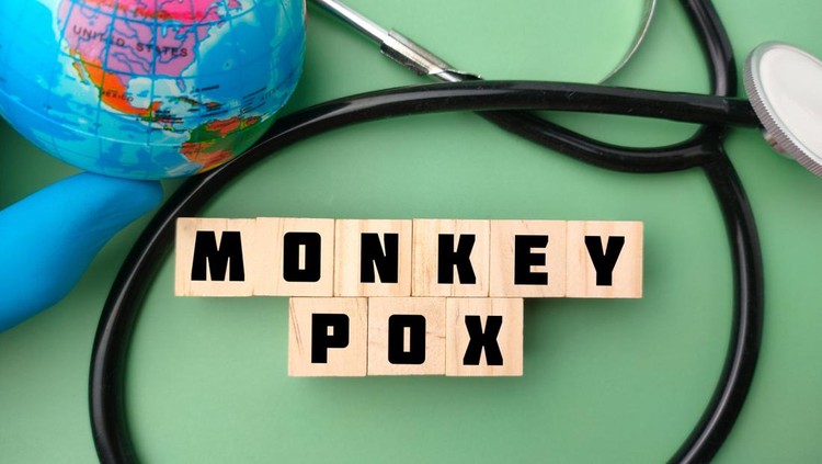 Top view hand holding earth globe and stethoscope with the word MONKEY POX on green background.