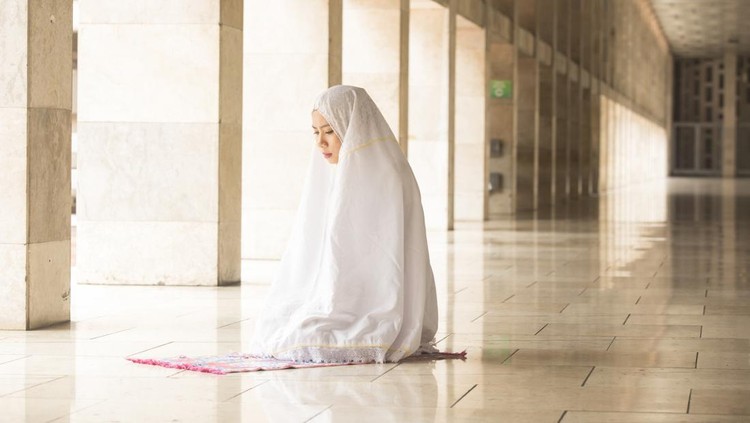Ilustrasi salat Muslim woman wearing prayer veil, praying in the mosque