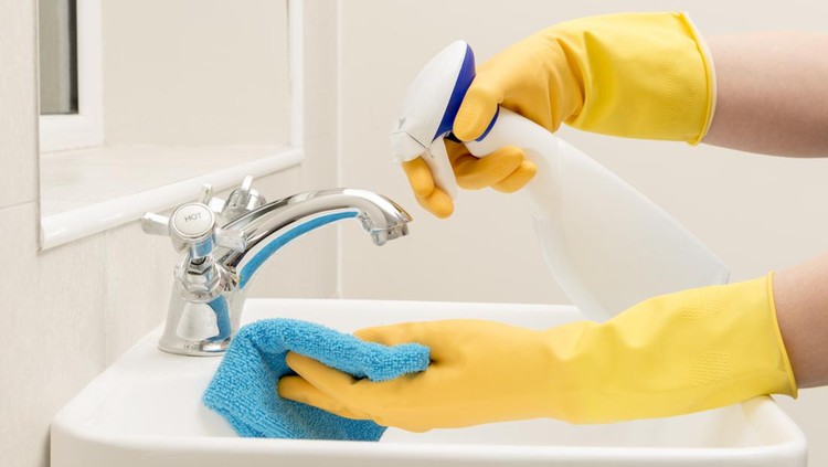 Ilustrasi wastafel kamar mandi Hands in gloves spraying liquid soap on a rag for cleaning bathroom sink