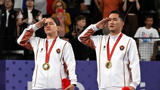 Paris 2024 Paralympics - Badminton - Mixed Doubles SL3-SU5 - Medal Ceremony - Porte de La Chapelle Arena, Paris, France - September 2, 2024Gold medallists Ramdani Hikmat and Leani Ratri of Indonesia salute as they sing the national anthem on the podi