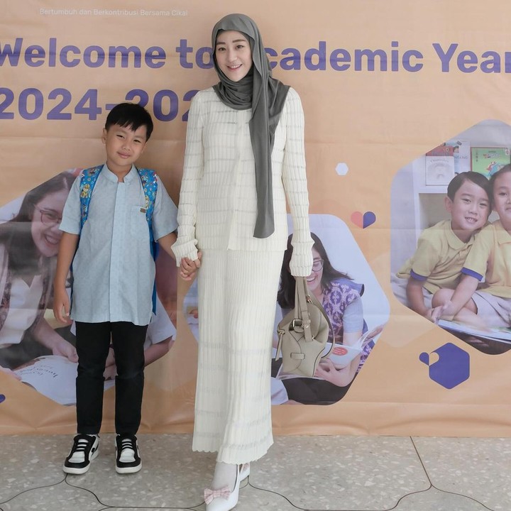 <p>Sejak menikah, Larissa tetap sibuk menjalankan tugasnya sebagai Bunda dua anak. Hal itu tak membuatnya mati gaya, Bunda. Ia tetap terlihat modis saat mendampingi sang putra, Yusuf di sekolah. Larissa mengenakan <em>cardigan</em> dan rok berwarna putih gading yang dipadukan dengan sepatu beraksen pita. Ia kembali mengenakan hijab pashmina yang menjuntai di bahu sebelah kiri. (Foto: Instagram @larissachou)</p>