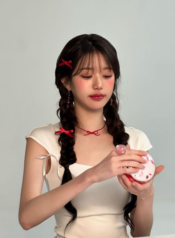 Tampilan Wonyoung tidak henti menjadi inspirasi, kali ini ia menata rambutnya dengan kepang dua dan menambah aksesori pita merah seperti boneka hidup. Ia juga memakai anting dan kalung merah yang match dengan outfitnya. / Foto: Instagram/for_everyoung