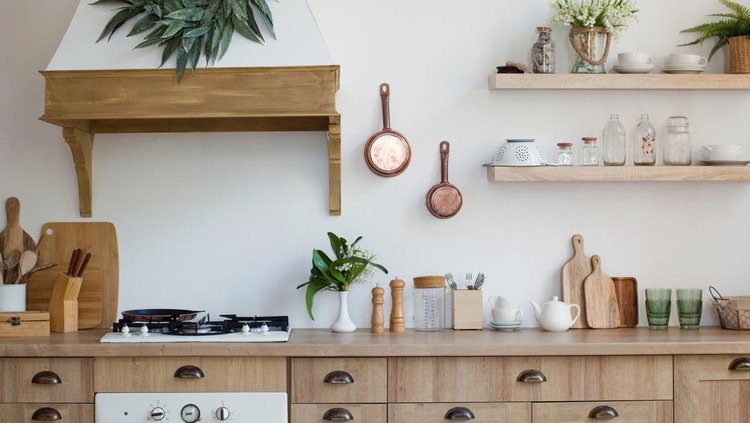 Light wooden kitchen interior with kitchen utensils on the shelves and on the wall. Beautiful kitchen interior design