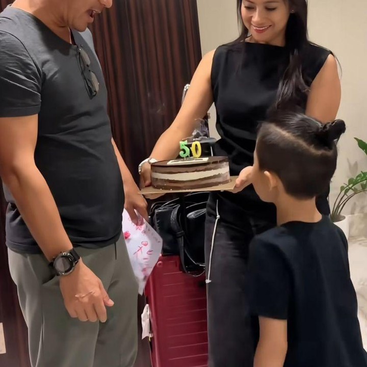 <p>Ririn membawa kue ulang tahun yang dilengkapi lilin angka 50 dan sang putra membawa kertas berisi tulisan selama ulang tahun untuk sang Ayah. (Foto: Instagram@riniyulianti)</p>