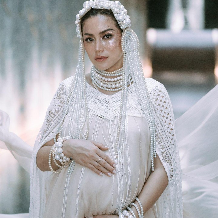 <p>Aktris dan presenter Jessica Iskandar kerap memamerkan baby bump kehamilannya dengan konsep photoshot yang berbeda. Dalam potret ini, Jessica Iskandar memamerkan riasan bold yang didominasi warna putih dengan aksesoris mutiara. (Foto: Instagram @inijedar)</p>