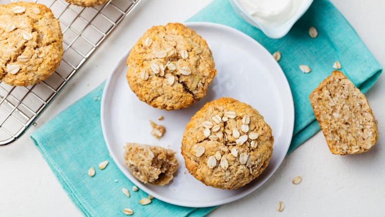 Banana oat muffin Healthy vegan oat muffins, apple and banana cakes with sour cream on a white plate. Blue stone background. Top view