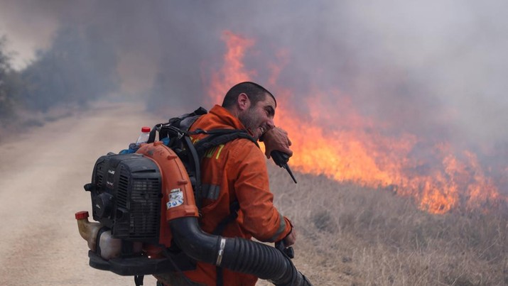 A man reacts as he attempts to extinguish flames following a rocket attack from Lebanon, amid cross-border hostilities between Hezbollah and Israel, in the Israeli-occupied Golan Heights September 20, 2024. REUTERS/Jim Urquhart