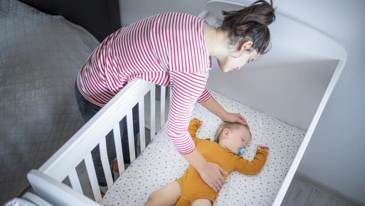 Caring young mother putting her baby boy for his nap.