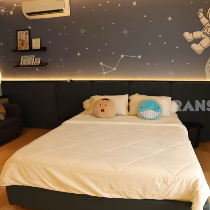 <p>Interior kamar Athar juga menarik perhatian. Selain ada seni mural astronout di tembok, susunan bingkai foto yang menempel, serta penataan lampunya membuat ruangan ini terasa hangat. (Foto: YouTube TRANS7 OFFICIAL)</p>