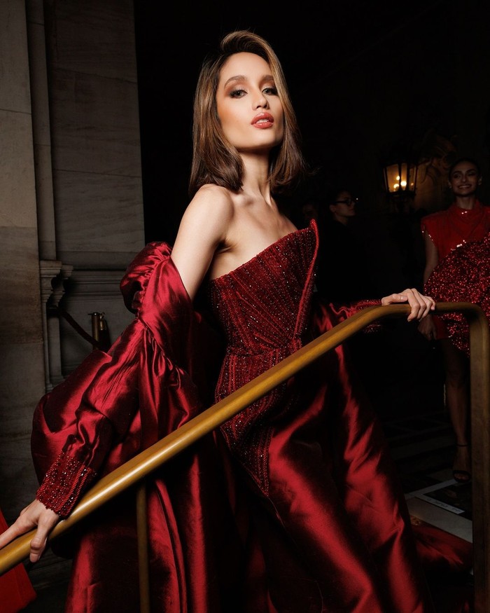 Cinta Laura tampil fierce dalam jumpsuit merah maroon, perpaduan gaya jumpsuit dan gaun jubah. Detail payet dan platform heels keemasan menambah kesan mewah dan berani pada penampilannya/Foto: instagram.com/lorealparis