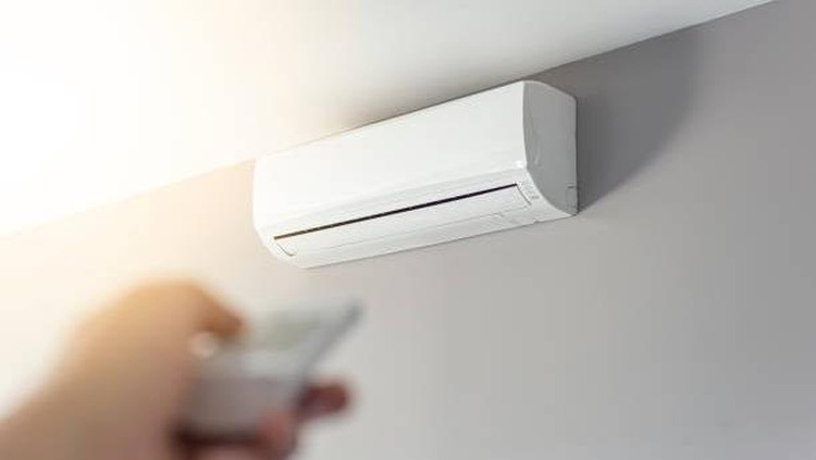A man shutting down the air conditioner with remote control. Selective focus on the air conditioner.
