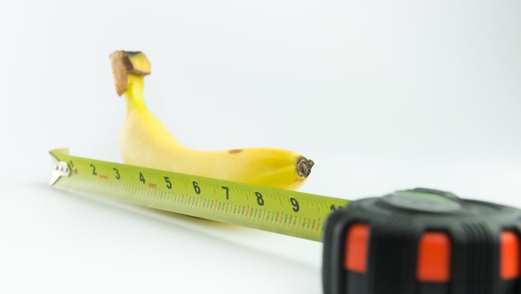 Close-up of measuring the size of banana on white background