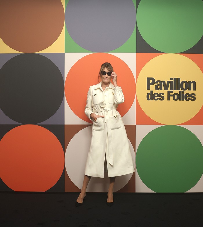 Carla Bruni Sarkozy kian atraktif dalam busana coat dress putih yang serasi dengan shoulder bag-nya. Istri mantan presiden Prancis itu sengaja mengenakan sepatu sederhana untuk memusatkan perhatian pada pakaian/ Foto: Courtesy of Valentino