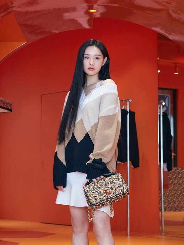 Kim Ji Won memilih gaya yang lebih feminin dan manis kala menghadiri event Burberry di Busan. Ia tampil ala ‘Cewek Bumi’ dengan dress putih yang dipadukan dengan oversize v-neck sweater berwarna earth tone./ Foto: Instagram/geewonii