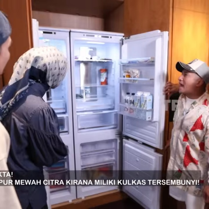 <p>Rumah ini juga memiliki banyak pintu kamuflase, salah satunya yang menyembunyikan kulkas seperti potret berikut ini. Ternyata, Ciki dan suami sepakat membuat rumah mereka terlihat lebih simpel termasuk dengan mengurangi penggunaan pintu yang tampil mencolok. "Kita tuh memang suka yang rapi, enggak banyak pernak-pernik, enggak banyak pintu-pintu. Makanya dibikin (pintu) kamufalase," kata Ciki.  (Foto: YouTube TRANS7 OFFICIAL)</p>