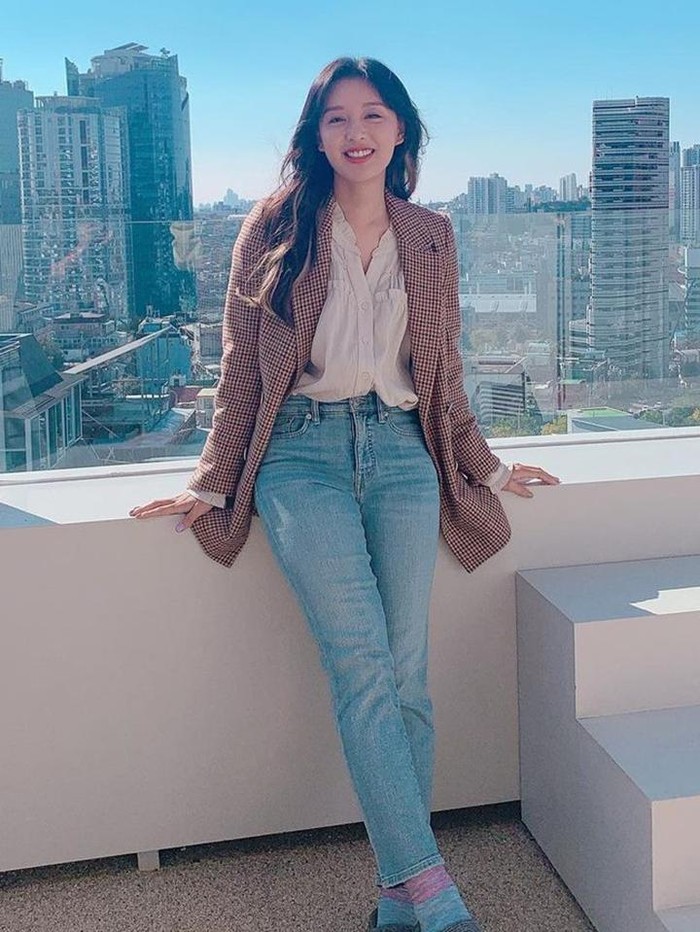 Saat mempromosikan drakor Lovestruck in the City pada 2020, Kim Ji Won tampil ala city girl dengan celana denim, blus, dan blazer berwarna senada. Rambut panjang tanpa poni membuat Kim Ji Won tampak lebih feminin dan dewasa./ Foto: Instagram/geewonii