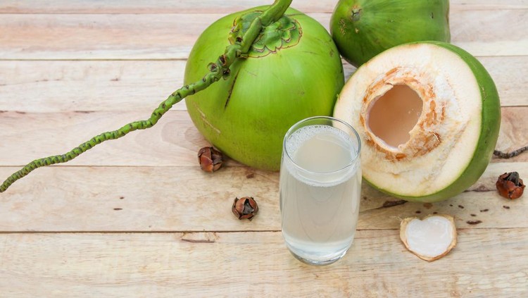 Fresh Coconut Water Drink in glass with coconut leaf on wooden  background
