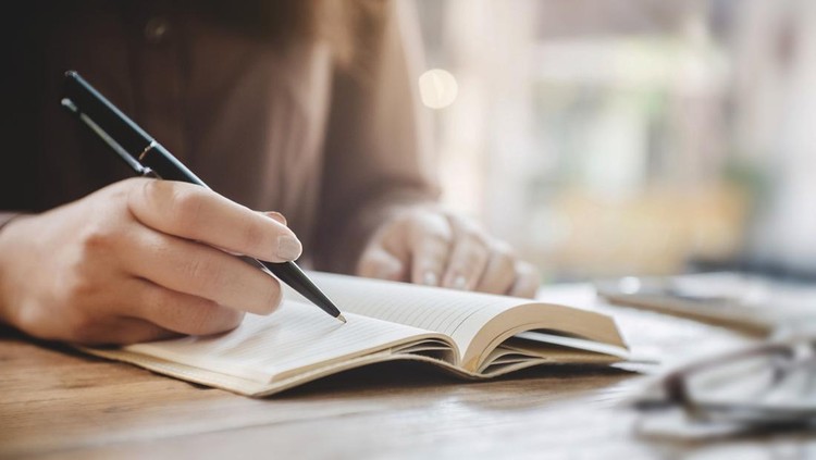 close up female hands writing on notebook at cafe.