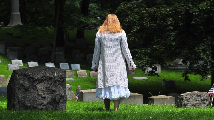 Pittsburgh, PA, USA - June 29, 2015: A woman walks in a cemetery on June 29, 2015 in Pittsburgh, Pennsylvania.