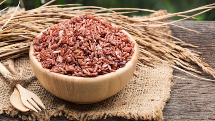 Brown rice in wooden bowl on gunny bag background