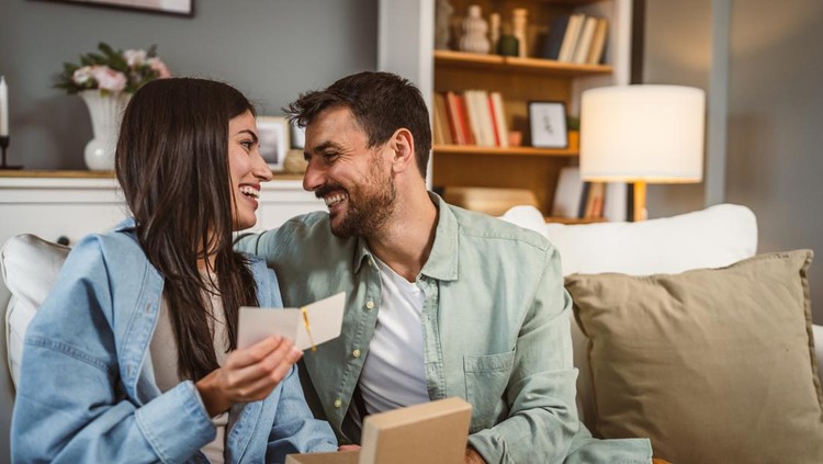 Girlfriend and boyfriend read birthday card greetings together at home