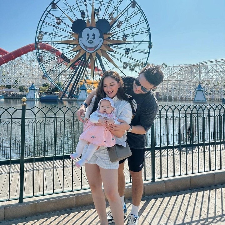 <p>Momen menggemaskan ini dibagikan langsung oleh Mila melalui laman Instagram-nya. Ketiganya terlihat berpose di depan bianglala dengan gambar Mickey Mouse. (Foto: Instagram: @jscmila)</p>