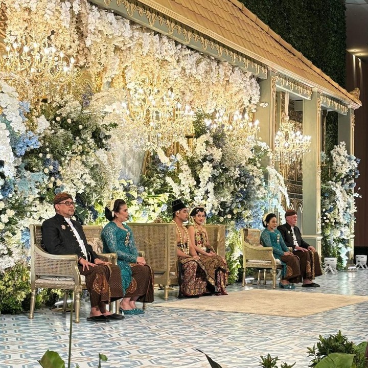 <p>Di acara resepsi, pasangan ini kembali mengenakan pakaian Jawa bernuansa batik klasik jawa dengan warna emas kecokelatan. Di acara resepsi ini, Anggika dan Omar duduk di pelaminan yang dihiasi dengan dekorasi bunga berwarna putih gading dan dedaunan hijau. (Foto: Instagram @anggikabolsterli)</p>