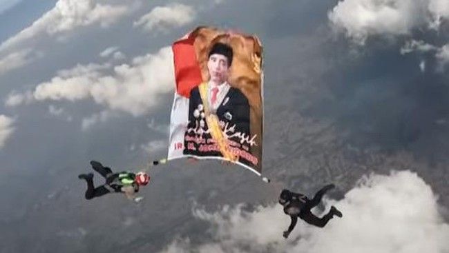 Tim terjun payung Polri membentangkan potret Presiden Jokowi dan Presiden terpilih Prabowo Subianto di langit Depok, Jawa Barat.