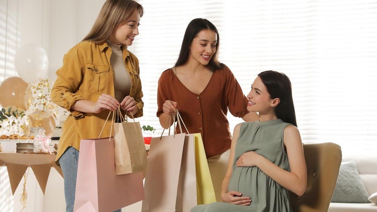 Happy pregnant woman spending time with friends at baby shower party
