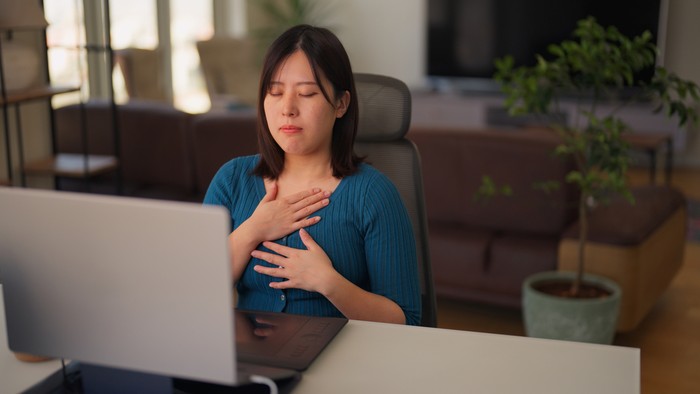 A freelancer businesswoman is taking a break from working and relaxing and doing breathing exercise in  the living room at home.