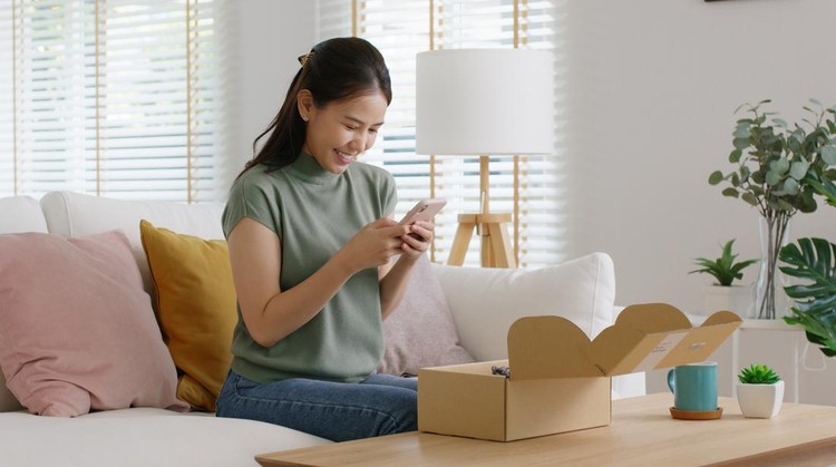 Young asia people happy girl smile unbox open gift buy order from online store shop take photo shoot camera post social media IG reel app show youth lifestyle blog share sit relax at home sofa couch.
