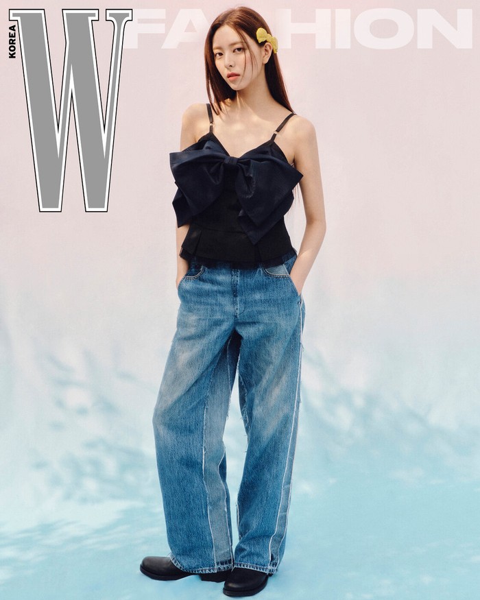 Yuna tampil cute dan girly dengan outfit dari Coach. Ia mengenakan atasan hitam taffeta bow top yang imut yang dipadukan dengan celana jeans. Ia melengkapi tampilannya dengan aksesori pita rambut yang lucu dan menggemaskan./ Foto: W Korea