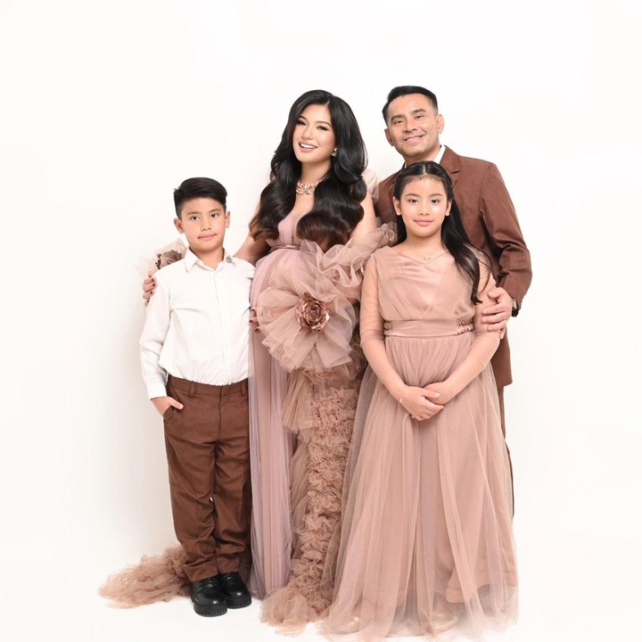 <p>Dalam <em>maternity shoot</em> ini, Duma Riris mengenakan gaun berwarna rose gold yang senada dengan gaun putrinya, Cleo. Sementera itu, Judika tampak mengenakan setelan jas berwarna cokelat yang senada dengan warna celana putranya Judeo. (Foto: Instagram @duma_riris)</p>