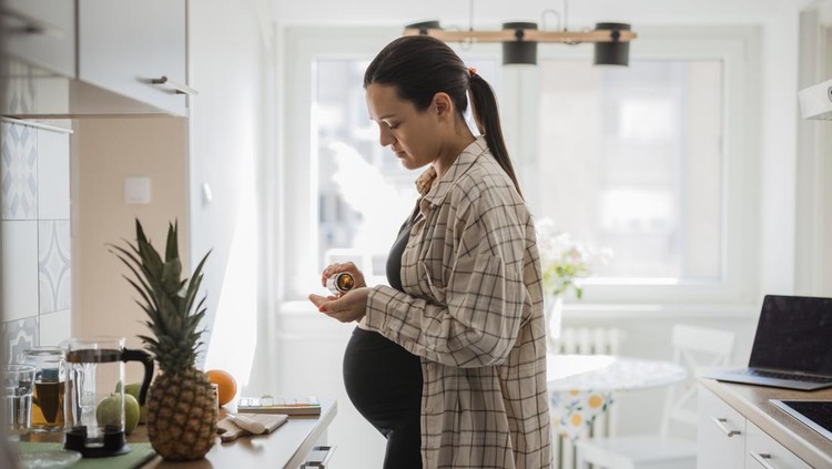 Pregnant woman using prenatal vitamin suplements during pregnancy