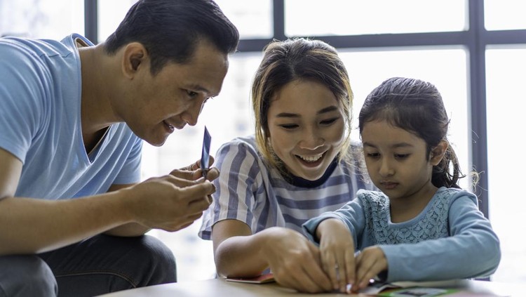 Mixed race Asian parents teaching daughter at home