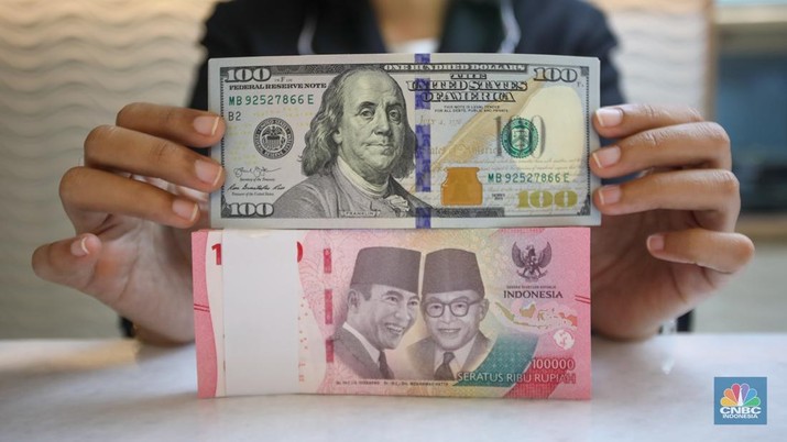 Petugas menunjukkan uang pecahan dolar AS dan rupiah di gerai penukaran mata uang asing di tempat penukaran uang PT Ayu Masagung, Jakarta, Senin (18/11/2024). (CNBC Indonesia/Faisal Rahman)