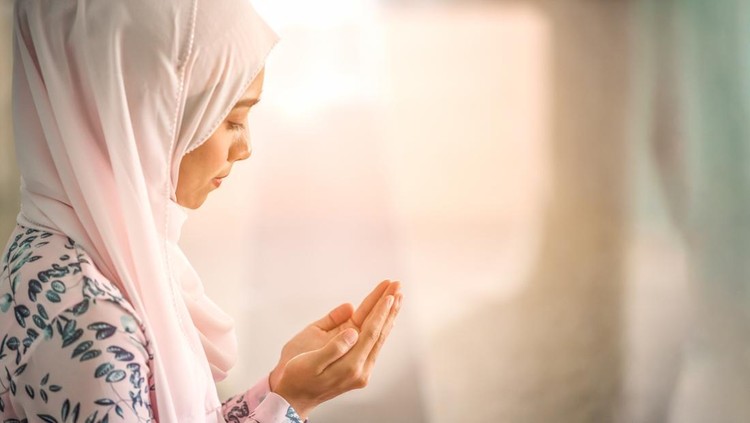 Young beautiful muslim women open palm, peaceful praying in mosque.