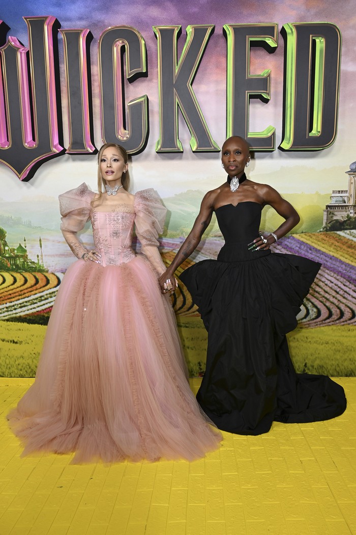 Untuk premier di Australia (3/11), Ariana Grande tarik inspirasi dari karakter yang diperankannya, Glinda. Ballgown rancangan Vivienne Westwood memiliki tulle bodice dan full skirt yang bertahtakan kristal peach. Ia turut memadukan perhiasan dari Lorraine Schwartz dengan total lebih dari 100 karat. Kontras dengan Ariana, Cynthia mengenakan gaun strapless berstruktur peplum rancangan Louis Vuitton. Perhiasan Roberto Coin, mulai dari bros bentuk singa dikenakan sebagai choker, anting, cincin, sampai gelang menyempurnakan look-nya/ Foto: Getty Images/SAVERIO MARFIA