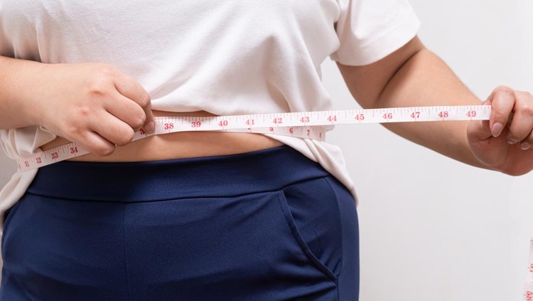 ilustrasi berat badan Close up shot at hand of women while use measure tape with her tummy or waist belly of chubby women that show sign of overweight. On white background with copy space for text