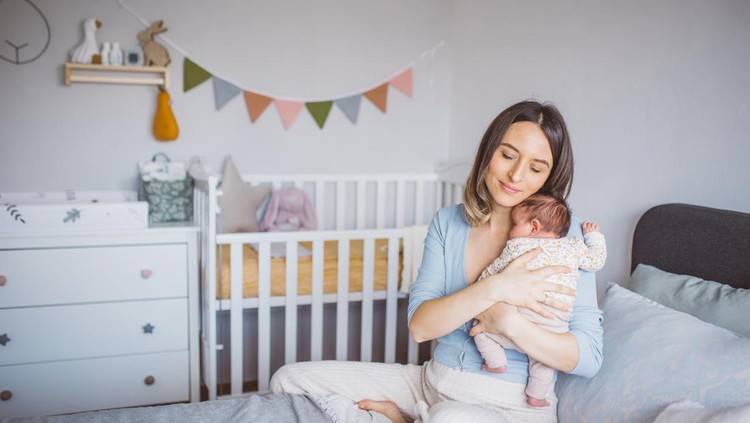 Mother holding a newborn baby in her arms. They are happy and enjoying in there time in nursery.