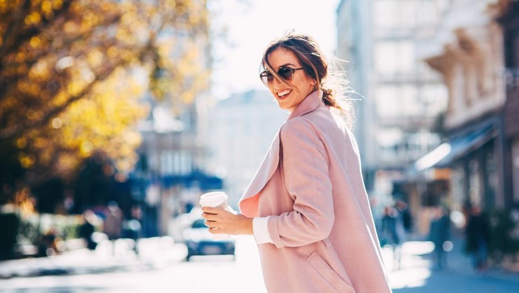 A young woman drinking coffee on her way to work.
