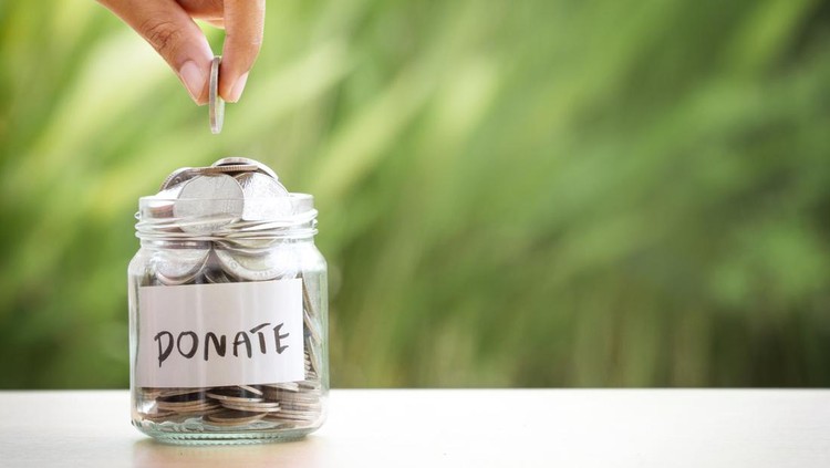 Hand putting Coins in glass jar for giving and donation concept