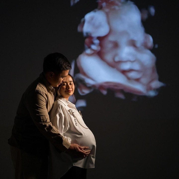 <p>Dalam foto ini, Gitte mengenakan baju berwarna putih, sementara suaminya Arif Hidayat memakai baju berwarna kuning kecokelatan. Keduanya berpose mesra dengan latar <em>background</em> foto USG anak pertama mereka. (Foto: Instagram @gritteagathaa)</p>