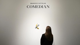 (FILES) People look at Italian visual artist Maurizio Cattelanís duct-taped Banana entitled "Comedian," during a press preview at Sotheby's in New York, on October 25, 2024. A fresh banana taped to a wall -- a provocative work of conceptual art by I