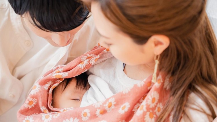 Mother breastfeeding her baby with father