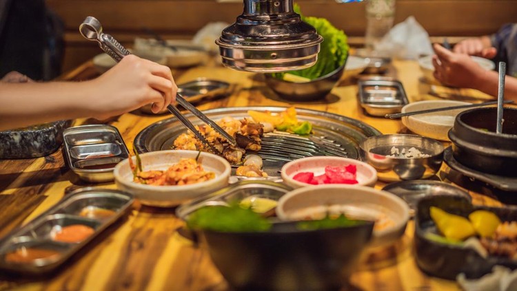Woman grilling barbecue on mesh grill of charcoal fire. Korean or japanese traditional food grilling style barbecue.