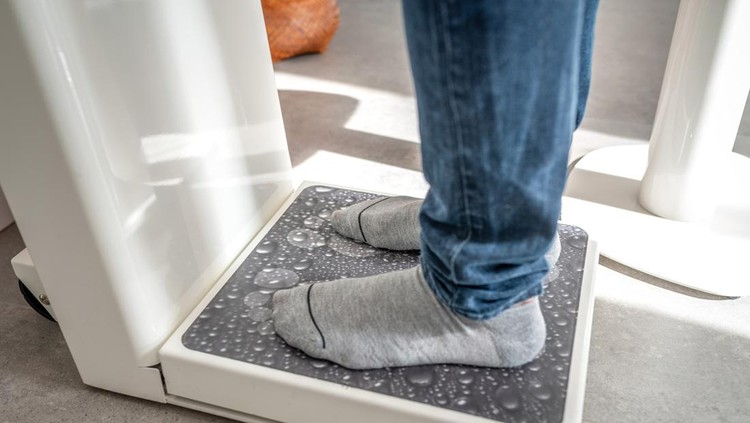 Ilustrasi turun berat badan Male on weight scale on floor background, Diet concept.