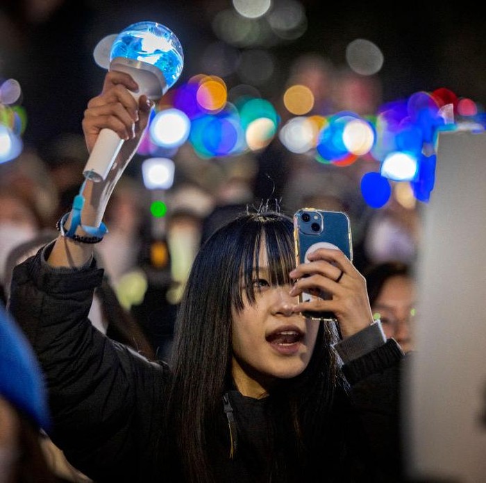 SEOUL, SOUTH KOREA - DECEMBER 08: Protesters wave K-pop light sticks as they take part in a protest against the president outside the National Assembly on December 08, 2024 in Seoul, South Korea. President Yoon Suk Yeol survived an impeachment vote on Saturday after a boycott by ruling party lawmakers, following his controversial declaration of martial law which sparked widespread public outrage and political turmoil. (Photo by Ezra Acayan/Getty Images)